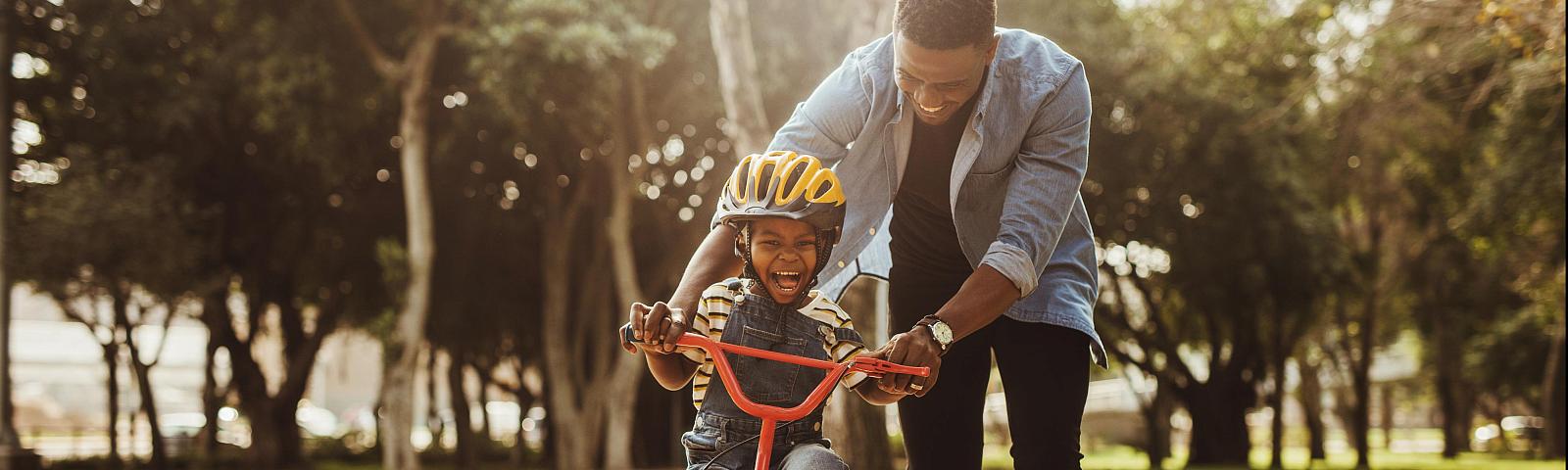 boy learning how to ride bike with dad